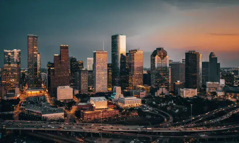The downtown Houston skyline at dusk, above the freeway interchanges
